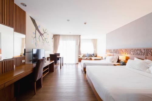 a hotel room with two beds and a television at Areca Lodge in Pattaya