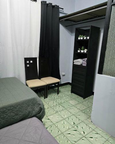 a bedroom with a bed and two chairs and a dresser at Departamento Completo en el Centro de Monterrey in Monterrey