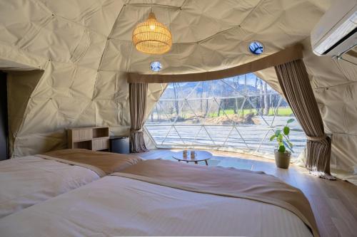 a bedroom with two beds and a large window at Private Glamping NAGOMI CAMP in Nasushiobara