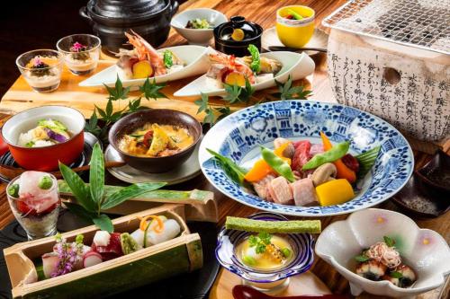 a wooden table with plates of food on it at Bessou Konjakuan in Yufu