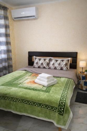 a bed with a green comforter and towels on it at ApartHotel EURO in Cahul