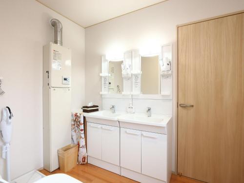 a bathroom with a white sink and a wooden door at Guesthouse&Café Deep in Kōzushima