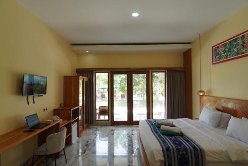 a bedroom with a bed and a desk with a computer at Salili Resort in Gili Islands
