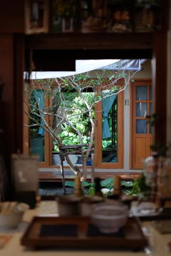 a window view of a tree outside of a door at Baannai Homestay & Flower Tea in Ban San Na Meng