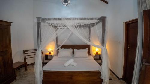 a bedroom with a canopy bed with white sheets and pillows at Dana Villa in Bentota
