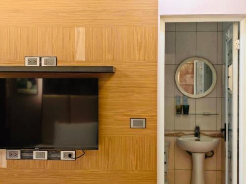 a bathroom with a sink and a television on a wall at Kinmen Harved B&B in Jinhu