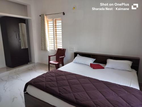 a bedroom with a large bed and a chair at Sharada Nest in Sringeri