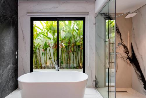 a bath tub in a bathroom with a window at Anoya Boutique Villa in Kerobokan
