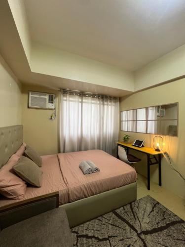 a bedroom with a bed and a desk with a laptop at Avida Tower 2 in Davao City