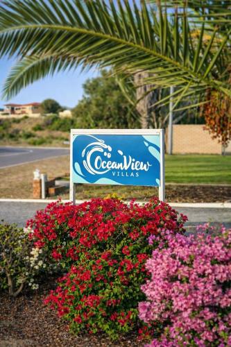 a sign for a ocean views villas with pink flowers at Ocean View Villas in Geraldton