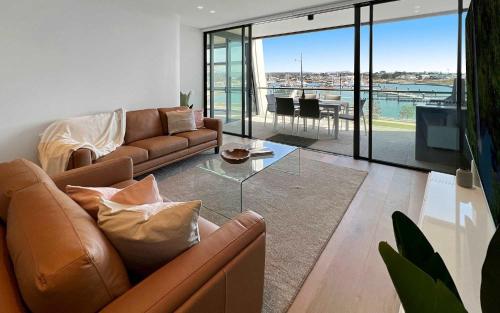 a living room with a couch and a glass table at Marina Vista - Waterfront Apartment in Shellharbour