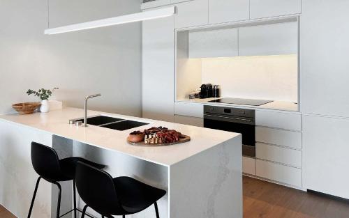 a kitchen with a counter with stools and a plate of food at Marina Vista - Waterfront Apartment in Shellharbour
