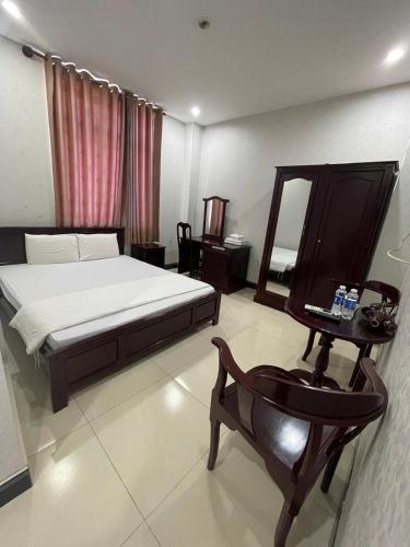 a bedroom with a bed and a table and a chair at Thi Long Phụng Hotel in Phú Quốc