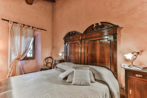 una camera con un grande letto con testiera in legno di Casa di Vignolo a Pergine Valdarno