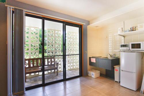 a kitchen with a large glass door leading to a balcony at Bise SMC Village in Motobu