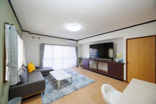 a living room with a couch and a tv at WAKE Inn 府中 in Fuchu