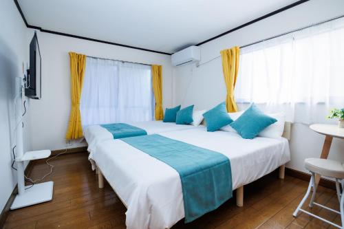two beds in a hotel room with blue pillows at WAKE Inn 府中 in Fuchu