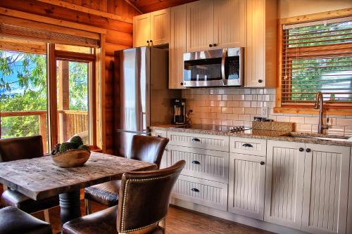 a kitchen with a table and chairs and a refrigerator at Wild Renfrew Seaside Cottages in Port Renfrew