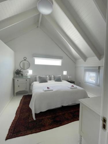 a white bedroom with a white bed and a window at Bougain Villa in Paternoster