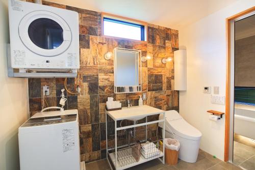 a bathroom with a sink and a washing machine at Bise SMC Village in Motobu