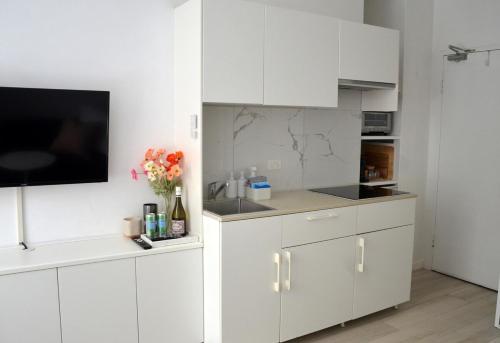 a kitchen with white cabinets and a flat screen tv at Cute Studio Apartment in Maroubra in Sydney