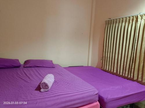 a purple bed with a towel on top of it at บ้านพักแอบสบาย abbsabyehome in Klong Wan