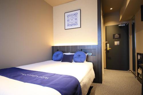 a bedroom with a large bed with blue pillows at Dynasty Hotel & Resort Osaka in Osaka