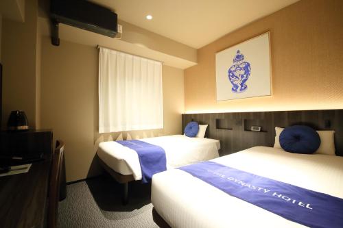 a hotel room with two beds and a television at Dynasty Hotel & Resort Osaka in Osaka