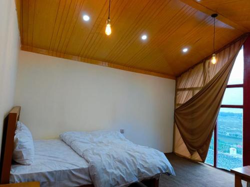 a bedroom with a bed and a large window at The Crescent Resort in Skardu
