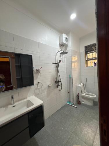 a bathroom with a shower and a sink and a toilet at Sunset Hideout Kulambiro in Kampala