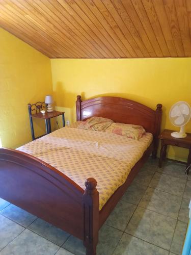 a bedroom with a wooden bed in a yellow wall at Ti caze memé étage in Saint-Philippe