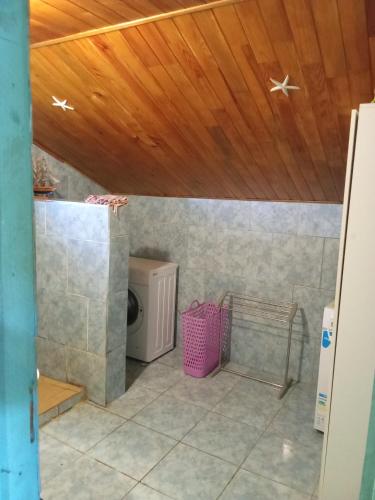 a bathroom with a washer and dryer under a wooden ceiling at Ti caze memé étage in Saint-Philippe