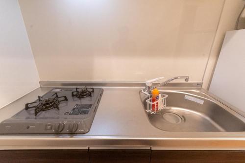 a kitchen counter with a stove and a sink at Rojuman Hakata in Hakata