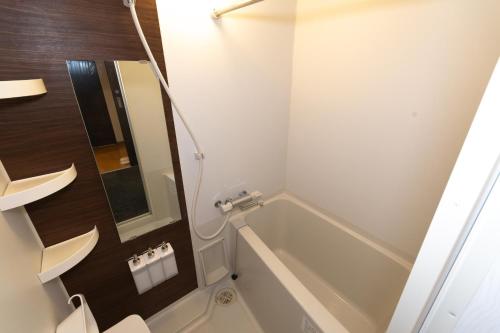 a bathroom with a tub and a toilet and a sink at Rojuman Hakata in Hakata