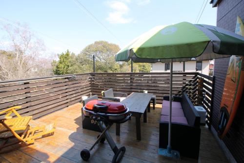 a grill on a deck with a green umbrella at Tomi house in Kariya