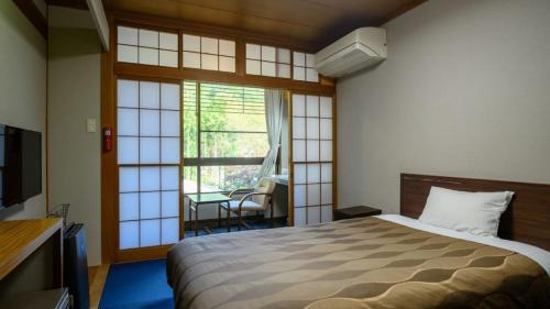 a bedroom with a bed and a large window at Iwaizumi Ryusendo Hotel Ryunosumika in Iwaizumi