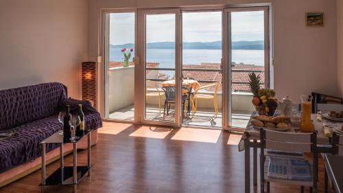 a living room with a couch and a table with a balcony at Villa Marina in Omiš