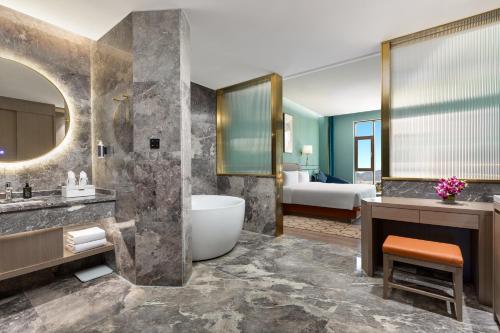 a bathroom with a tub and a sink and a bedroom at Wyndham Lijiang Yulong in Lijiang