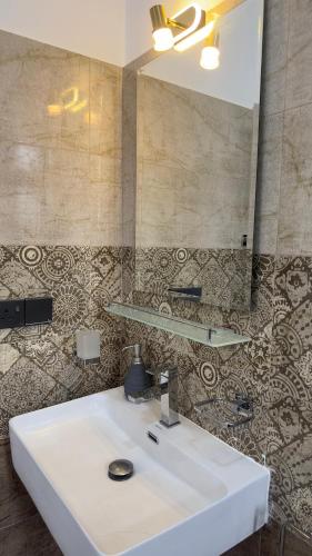 a bathroom with a white sink and a mirror at Lotus Manuvala - Negombo in Kochchikade