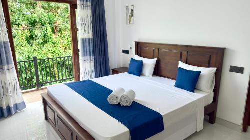 a bedroom with a large bed with blue and white pillows at Lotus Manuvala - Negombo in Kochchikade