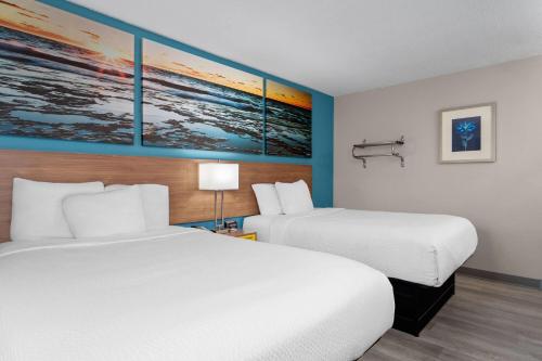 a hotel room with two beds and paintings on the wall at Days Inn by Wyndham Austin in Austin