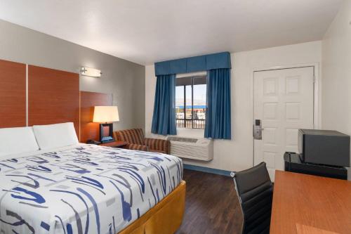 a small hotel room with a bed and a window at Travelodge by Wyndham Albuquerque West in Albuquerque