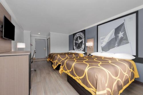 a hotel room with two beds and a flat screen tv at Super 8 by Wyndham Fort Worth Entertainment District in Fort Worth