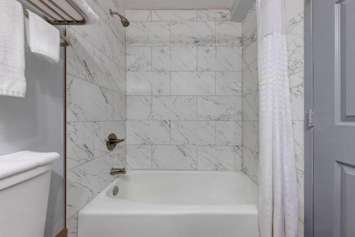 a white bathroom with a tub and a white shower curtain at Super 8 by Wyndham Fort Worth Entertainment District in Fort Worth