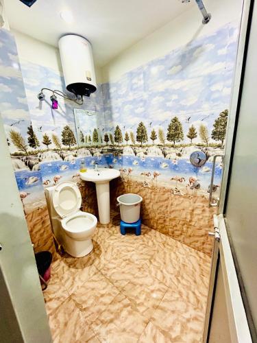 a bathroom with a toilet and a sink with a mural at Parvati home stay near by ramjhula,luxmanjhula in Rishīkesh
