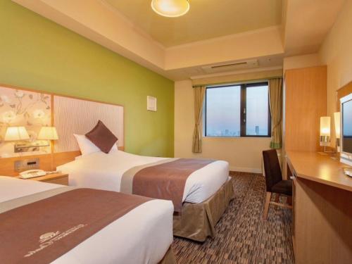 a hotel room with two beds and a desk at Hotel Monterey Grasmere Osaka in Osaka
