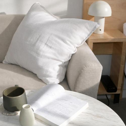 a white pillow and an open book on a couch at Cute Studio Apartment in Maroubra in Sydney