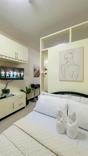 a bedroom with a white bed with white shoes on it at STUDIO WITH BALCONY at the HEART of DAVAO CITY in Davao City