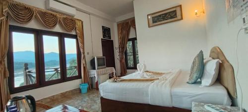 a hotel room with a bed and a large window at Phonevichith Riverside Hotel Houayxai in Ban Khonkèo