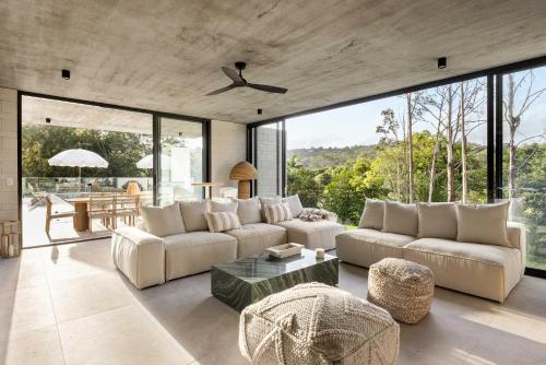 a living room with white furniture and large windows at Latitude 156 - Elevated Luxury Overlooking the Greens in Doonan